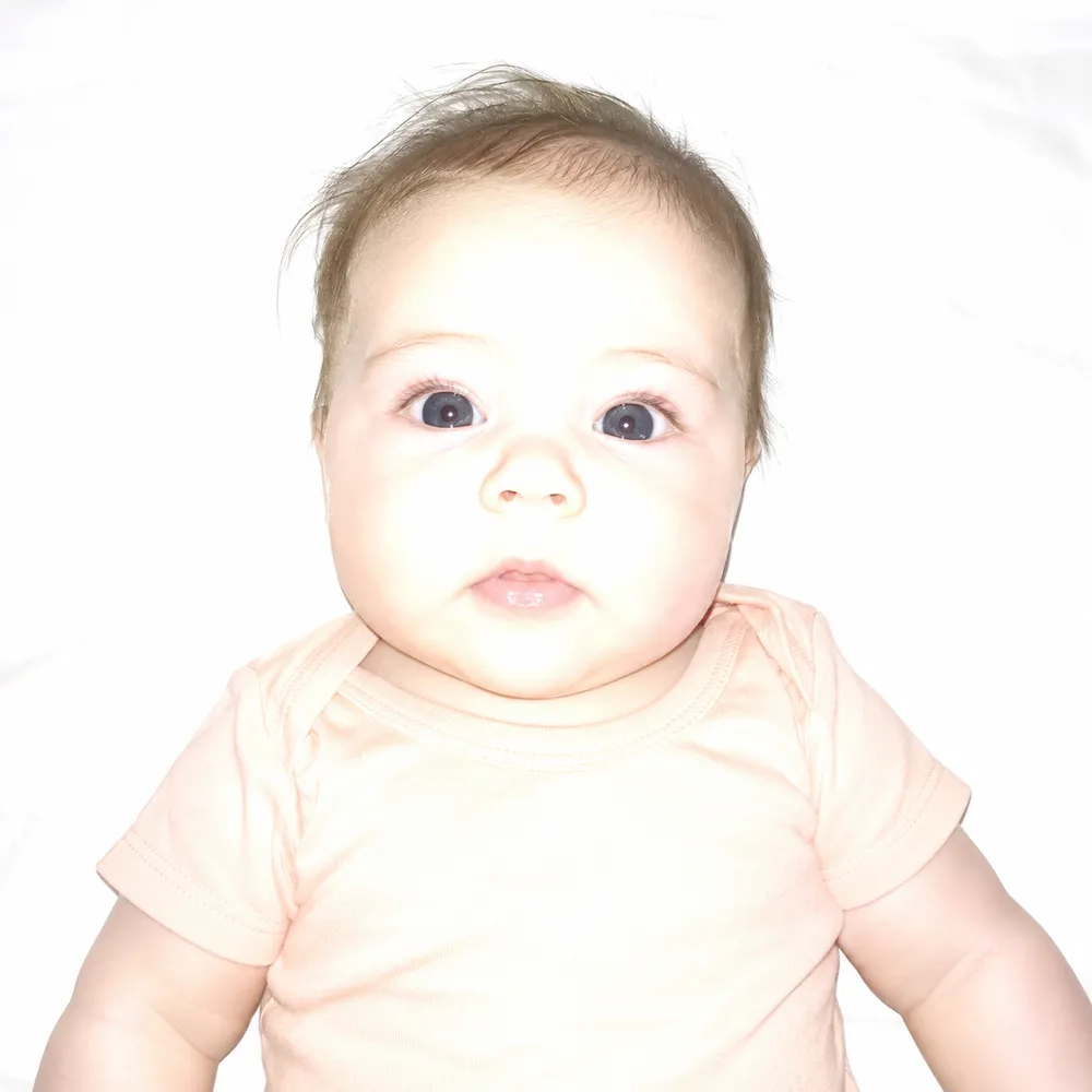 Rejected example: an overexposed photo where the baby's face and the sheet are washed out